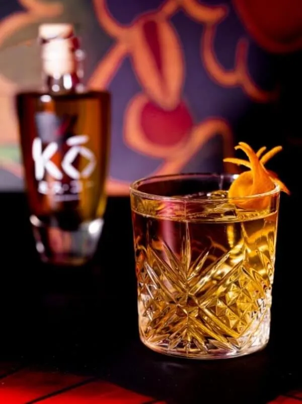 Miss Kō - Cocktail in a tumbler with a Miss Kō bottle in the background